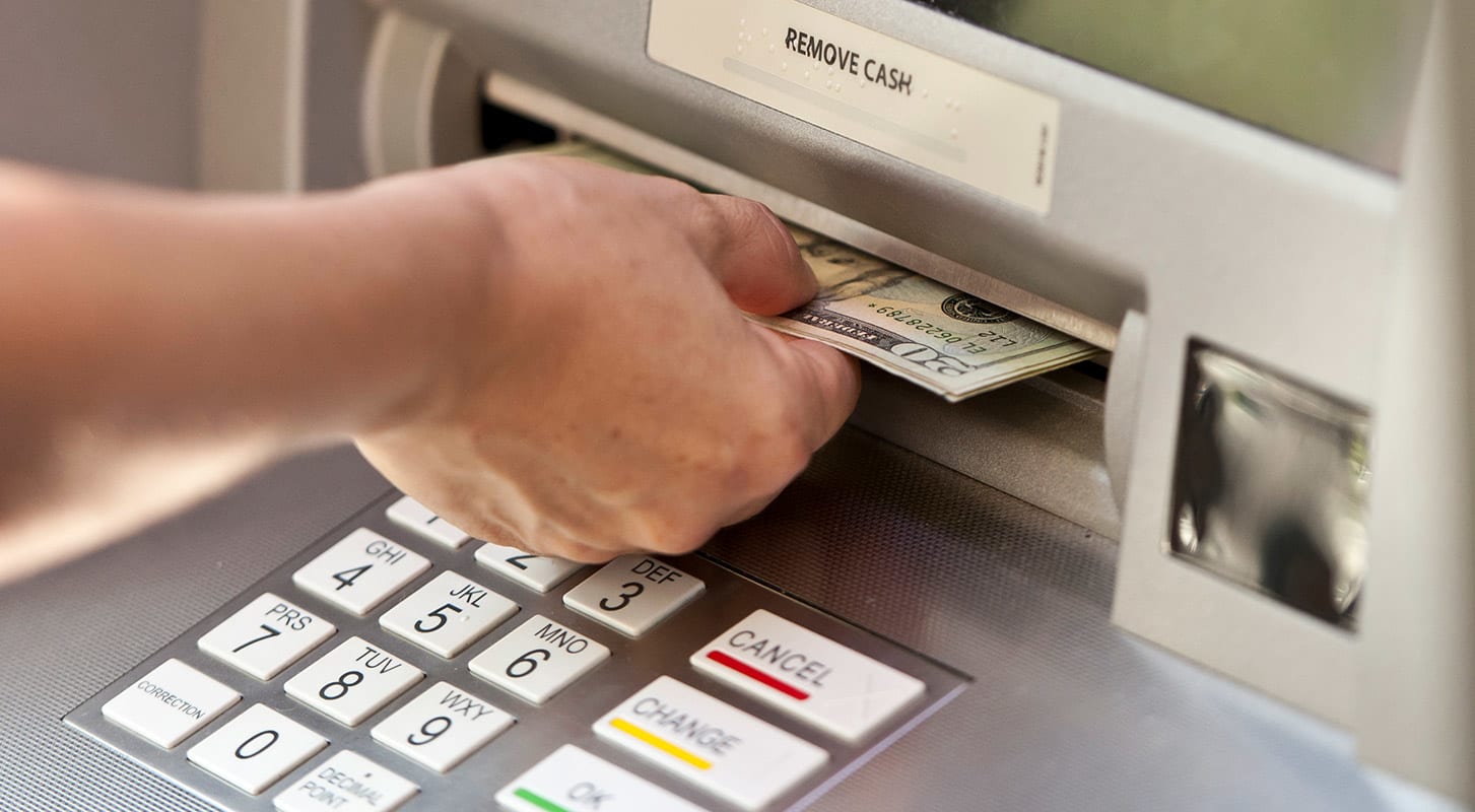 An individual is retrieving money from an ATM machine.